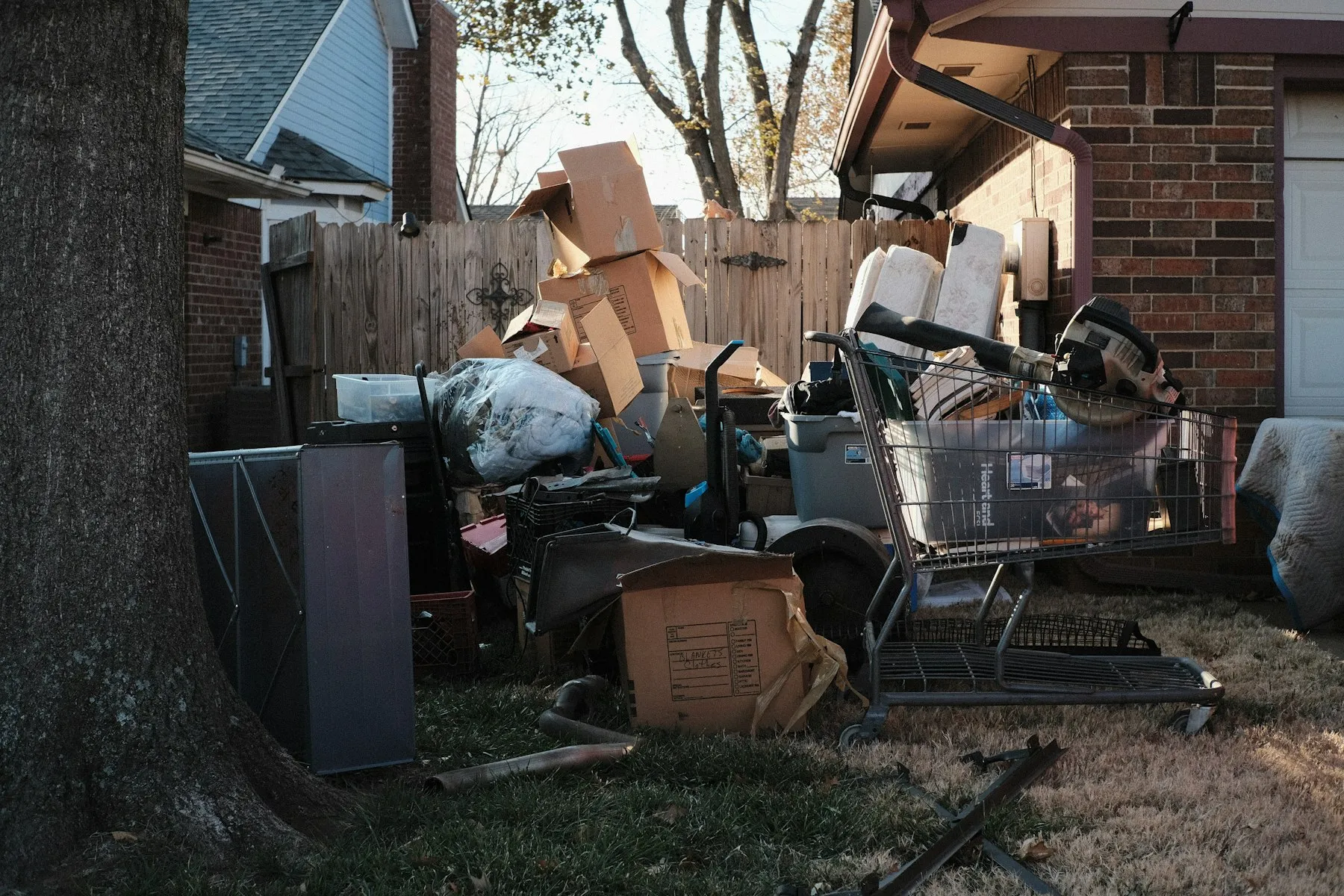 A pile of household junk stacked at the curb outside a home